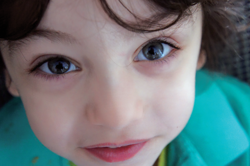 a child in a green shirt looking up at the camera