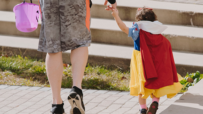 a child wearing a Snow White costume while trick or treating with a parent