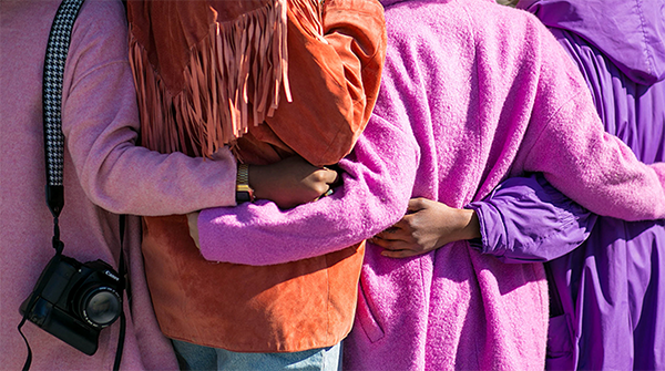 A group of people in purple jackets with their arms around each other