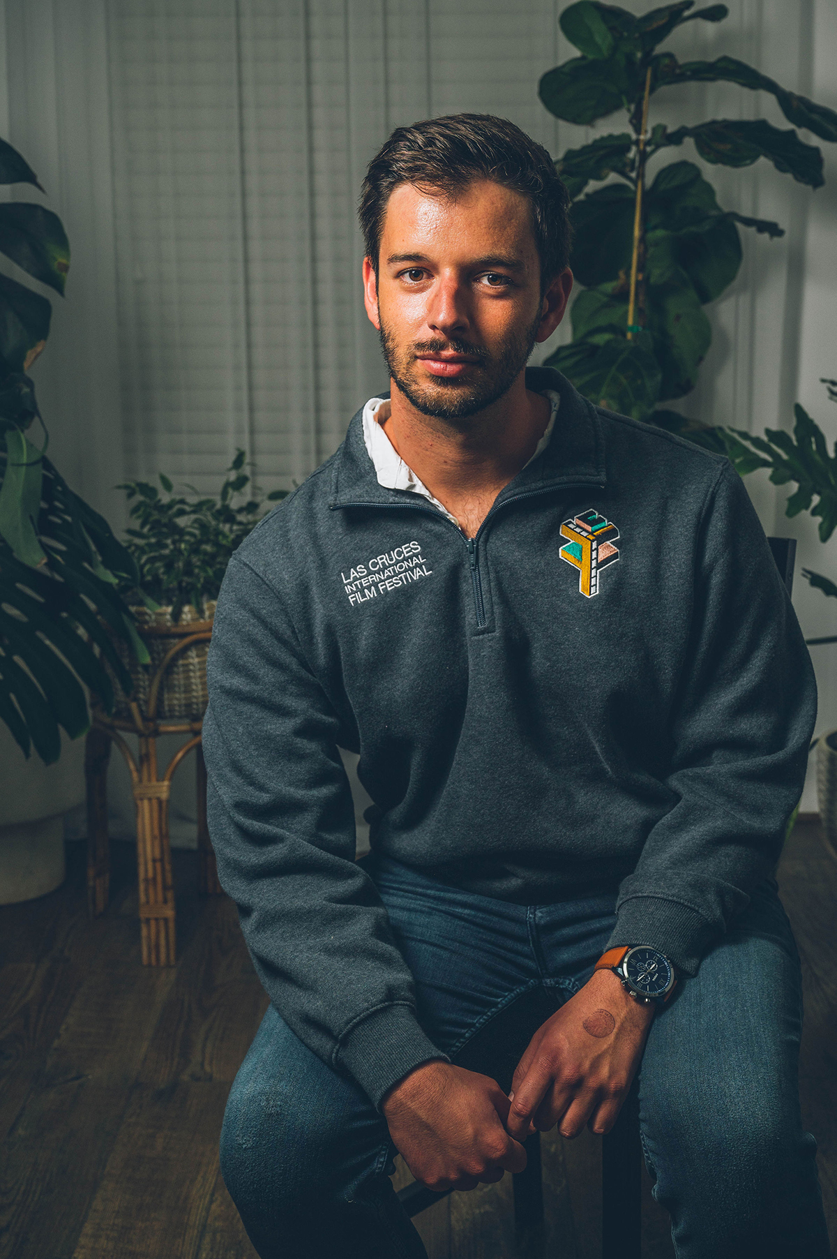 Alex sitting in a chair with house plants behind him