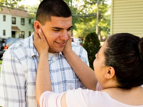 a mother looking at her son with her hands on his face