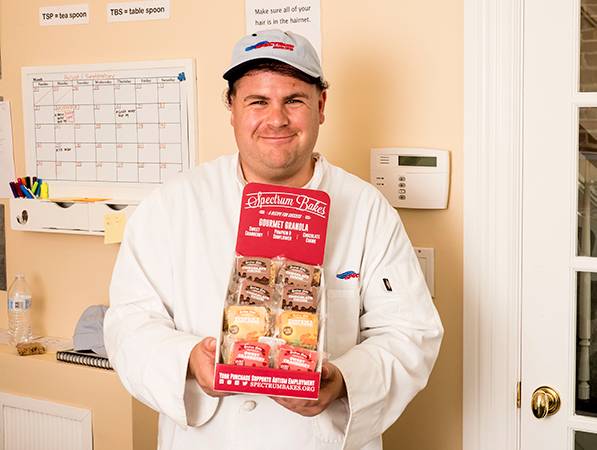 An employee at Spectrum Bakes smiling and holding products