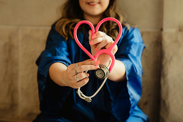 A school nurse holding up a stethoscope in the shape of a heart