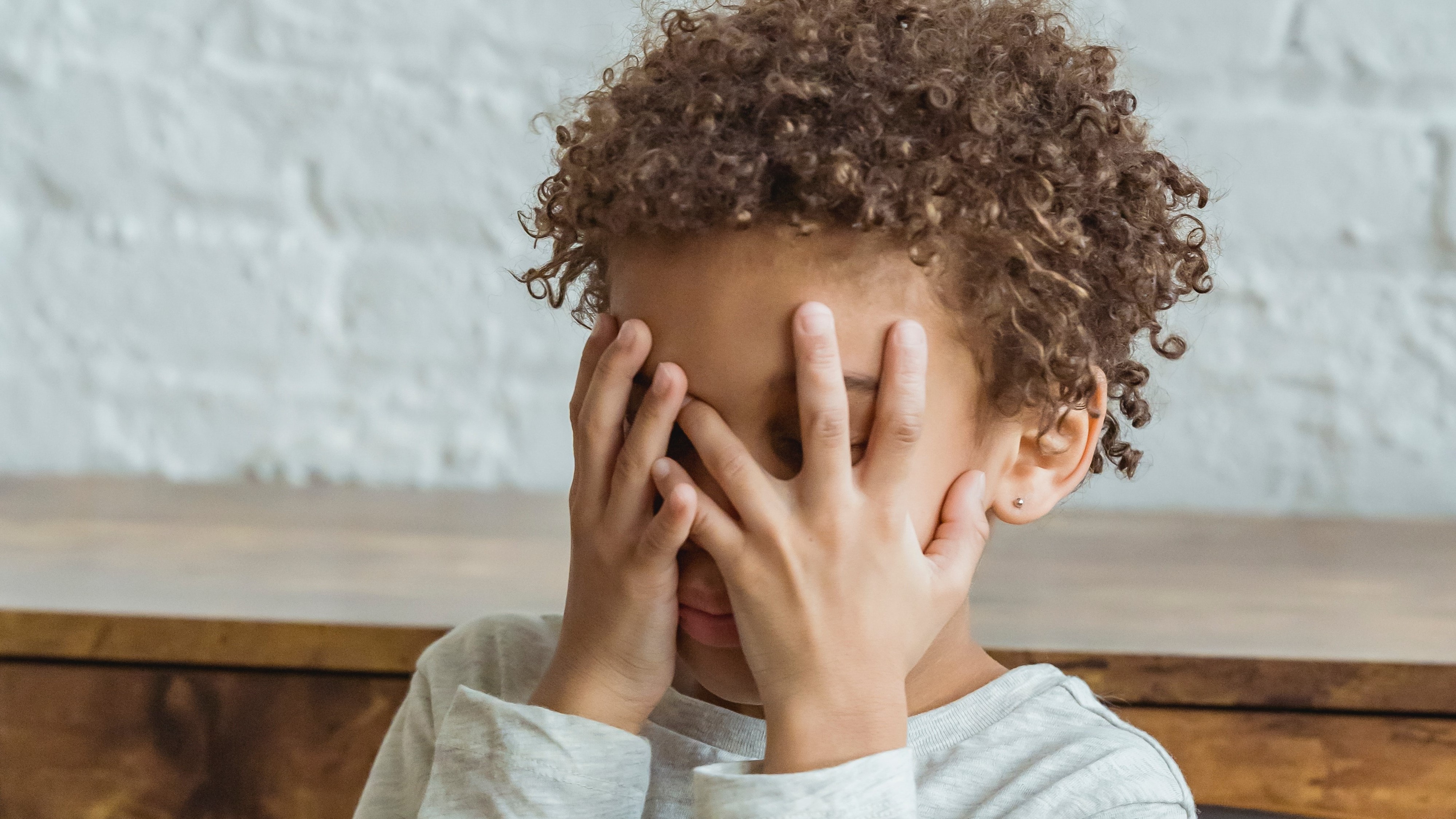 child covering their face with their hands