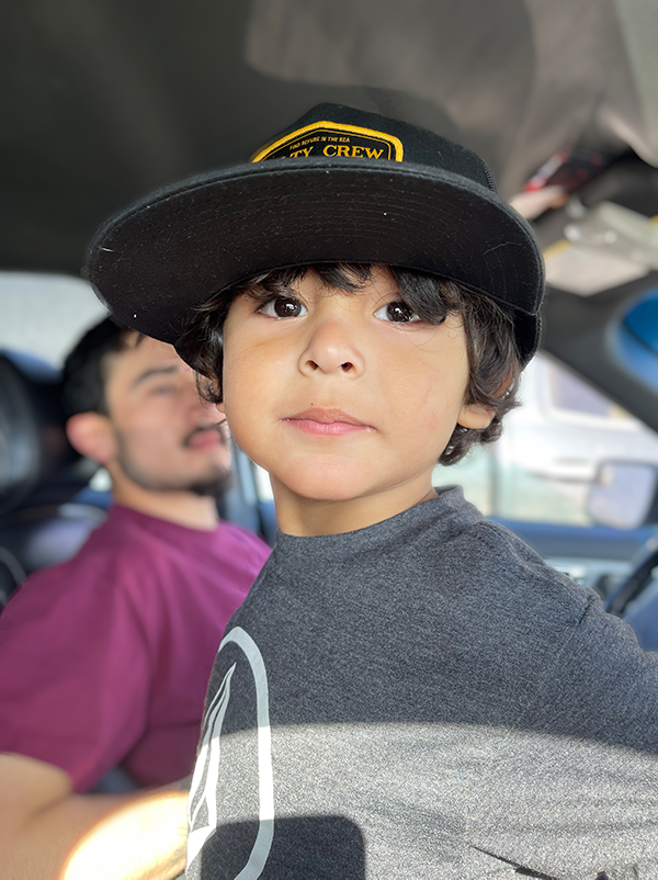 A toddler with dark hair wearing a hat