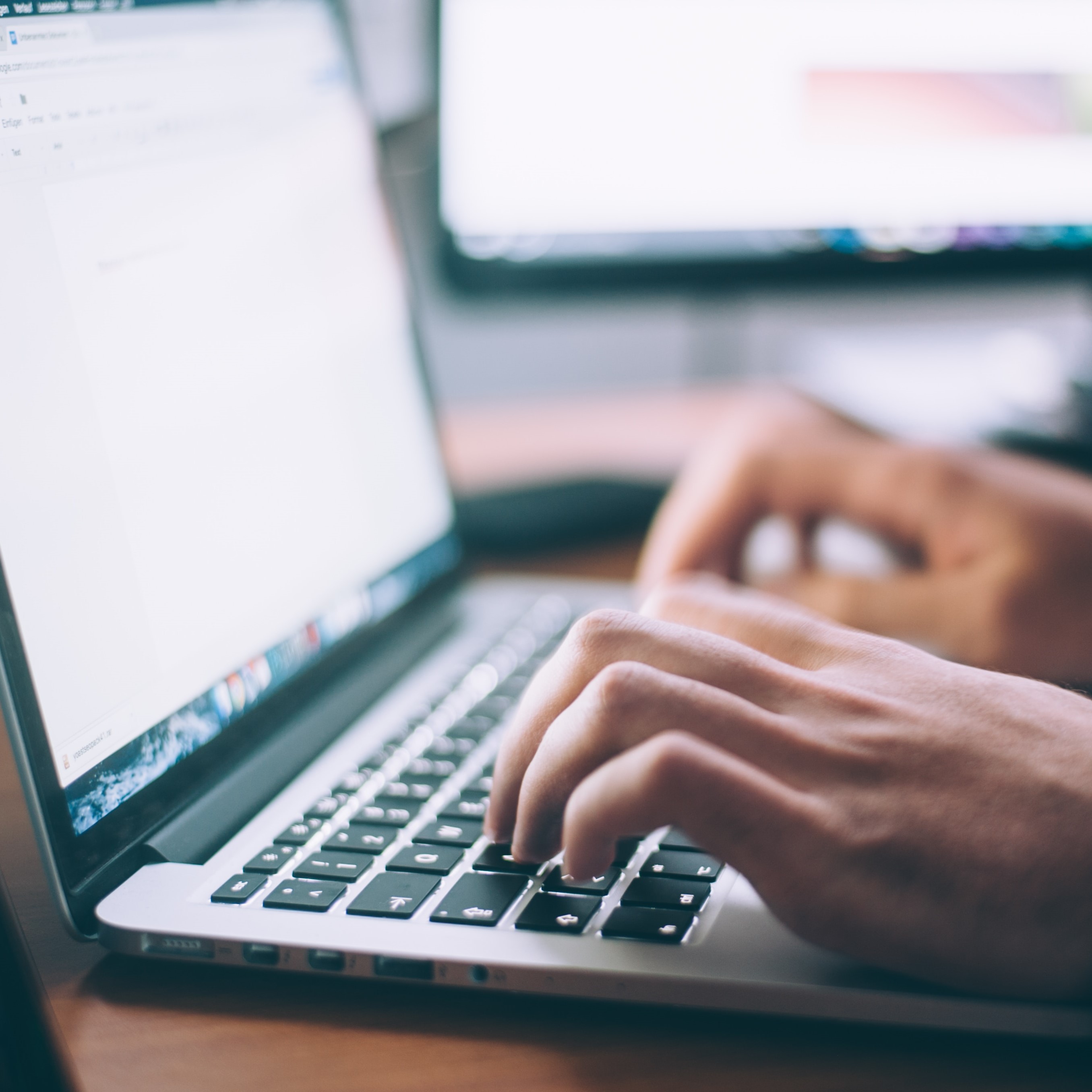 hands typing on a laptop keyboard