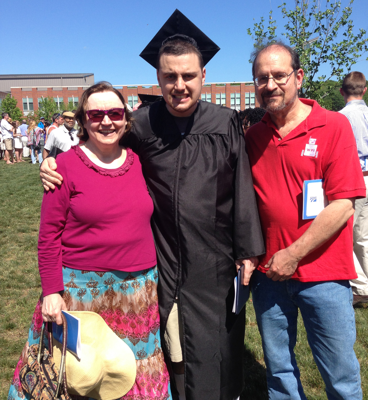 Ian H. wearing his cap and gown at graduation with his parents