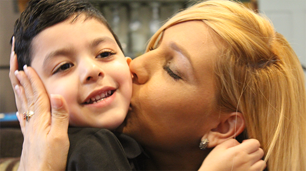  a mother kissing her young son on the cheek