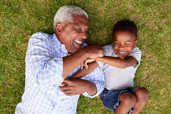 an adult and child laying in the grass laughing