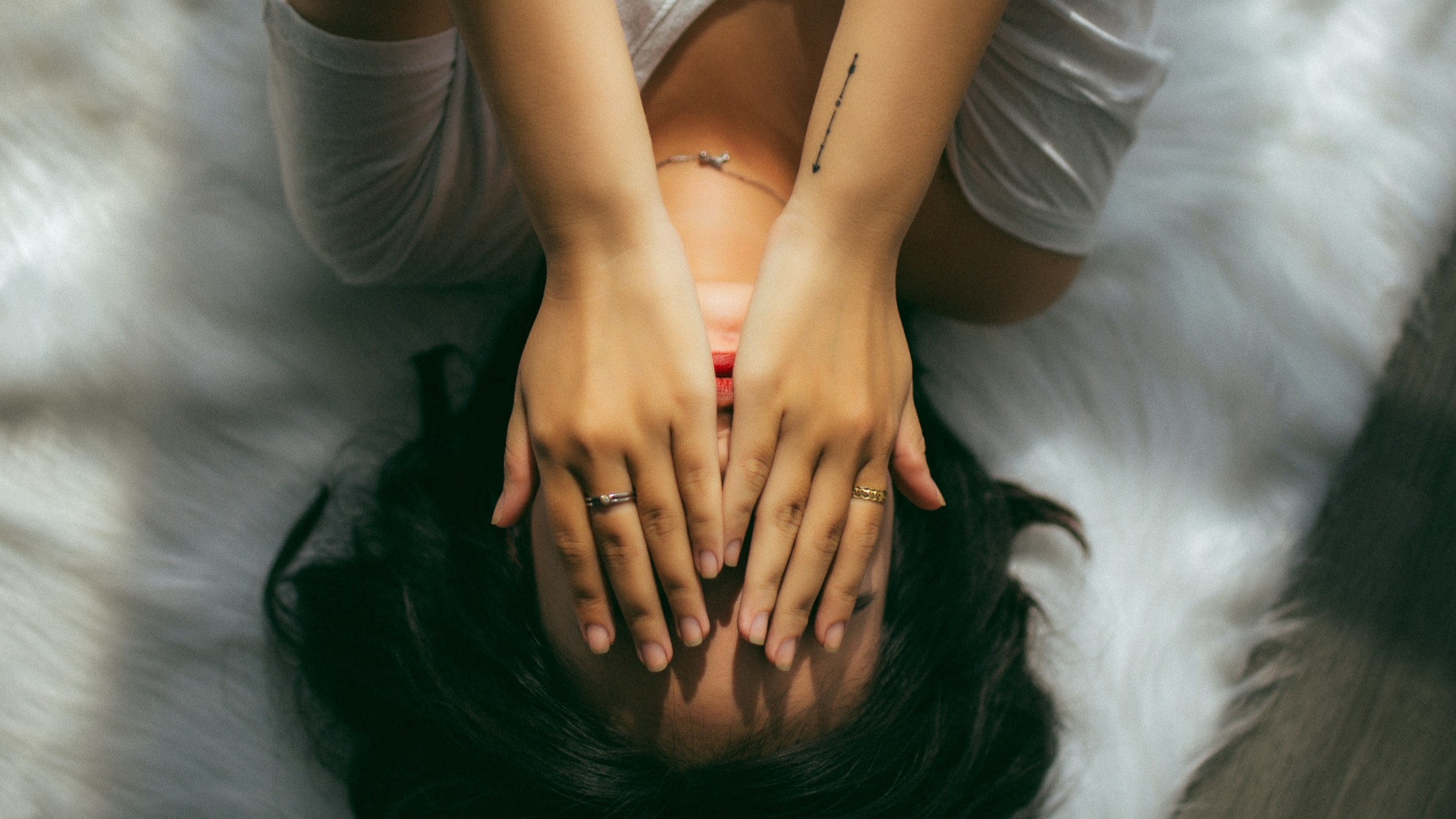 person laying on their bed with their hands covering their face