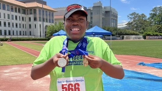 Seth smiling with his awards from the Special Olympics