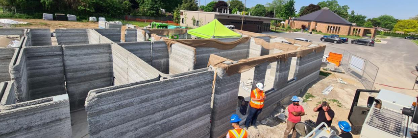Vue du dessus des murs en ciment d'un quadruplex avec des personnes à l’ouvrage au premier plan.