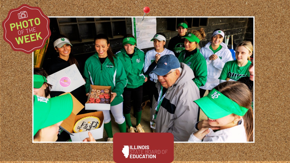 A group of people standing around a box of cake.