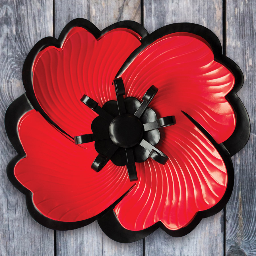 A vibrant red metal poppy that hangs on a wooden door