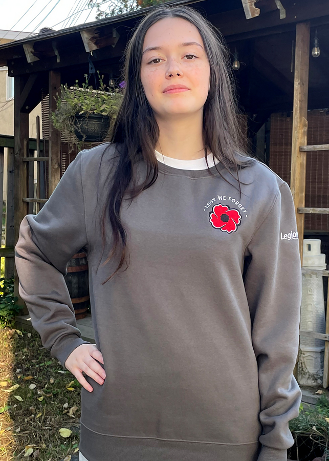 A woman wears a grey sweatshirt with Lest We Forget and the Legion poppy on left chest