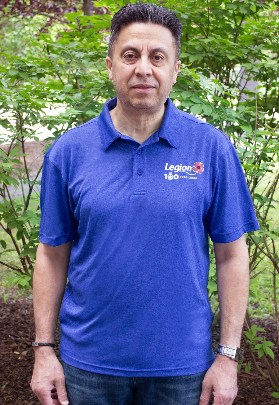 A man wears a cobalt blue polo shirt with the Legion Centenary logo